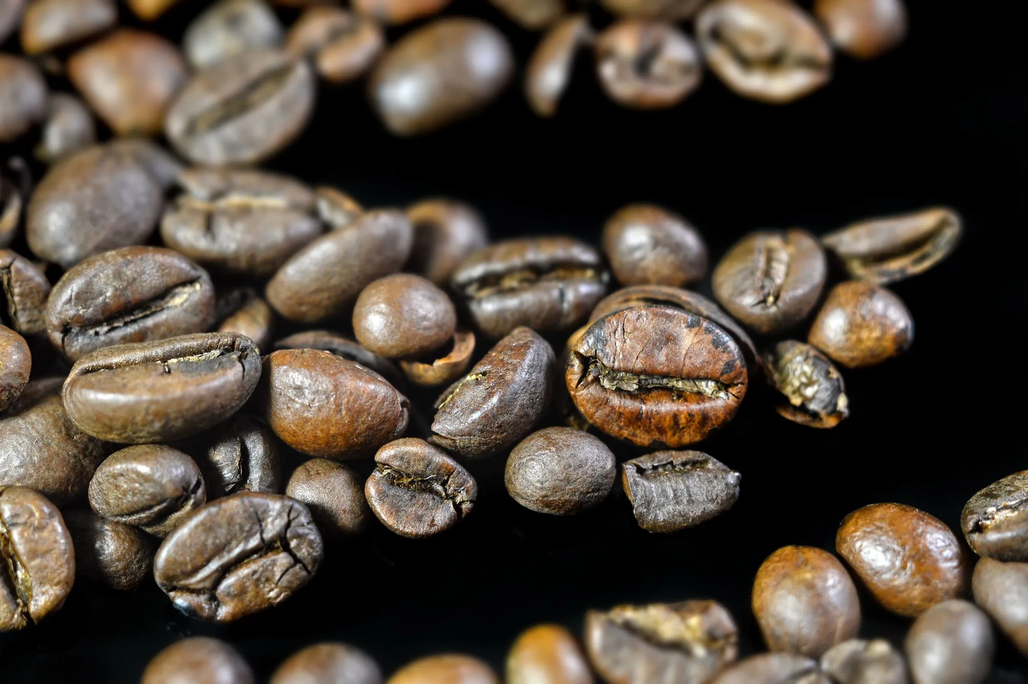 Grains de café torréfiés vus de très près sur un fond noir