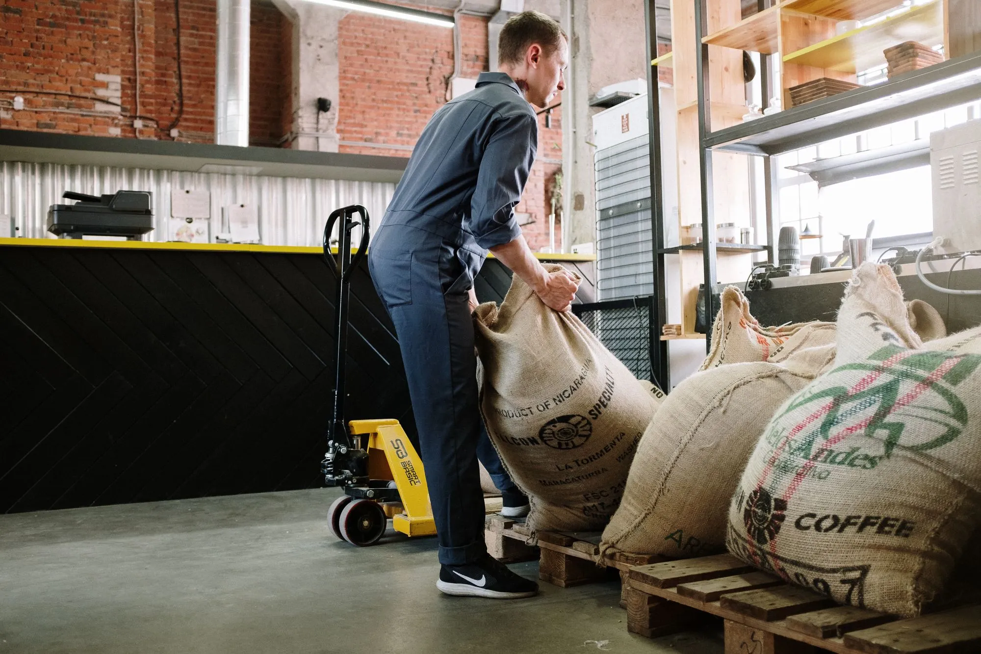 Manutention de sacs de café vert en toile de jute dans un dépôt