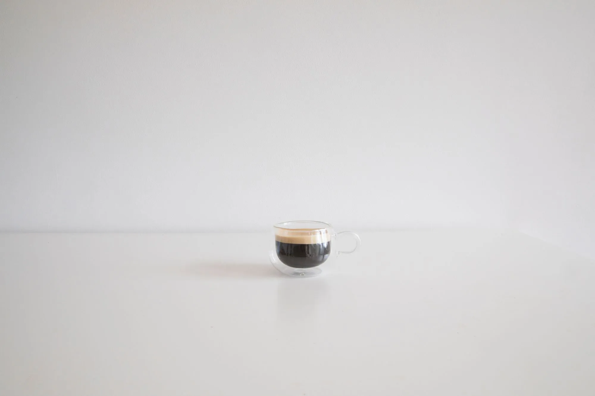 Une tasse d'expresso et sa crema, posée seule sur un plan clair
